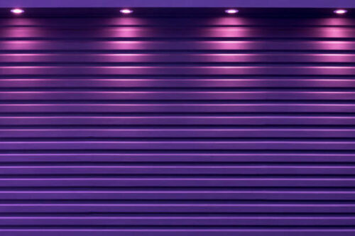 Purple lighting along the wall of the metal carport