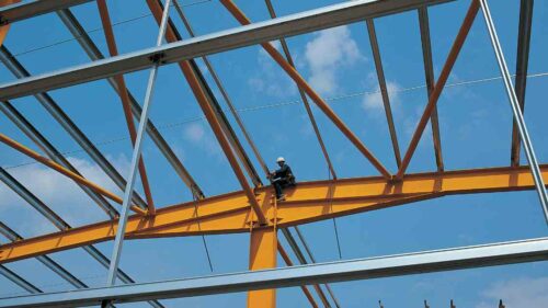 A person installing rafters of meta building