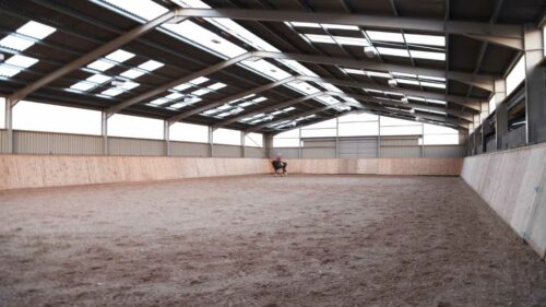 a person riding a horse in an indoor riding arena