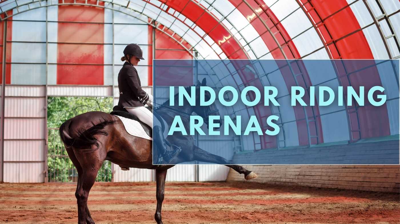 a person riding a horse in an indoor riding arena. The person is wearing a black helmet and a white shirt. The horse is brown with a white saddle and bridle. The arena has a red roof and white walls. The text “INDOOR RIDING ARENAS” is overlaid on the image in white text.