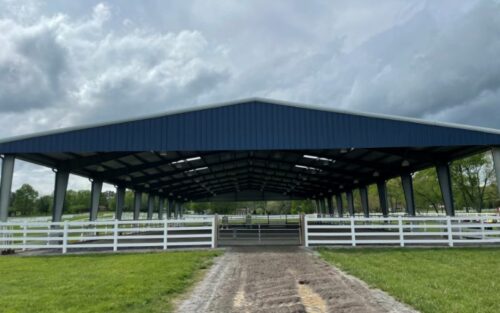 Blue-roofed 50x60 equestrian arena with white fencing