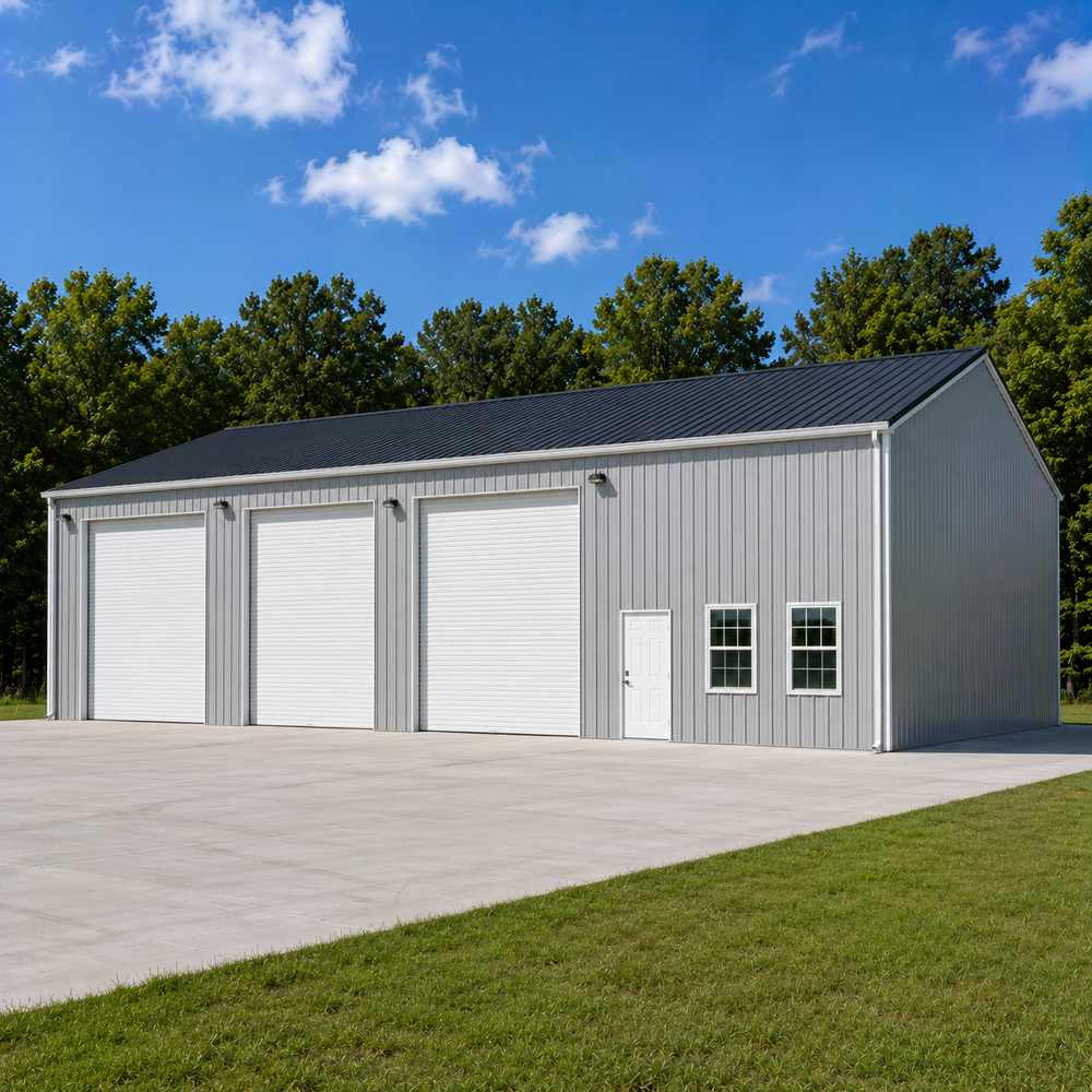 40x60 enclosed metal garage with three white roll-up doors, silver-gray walls and charcoal roof on paved driveway