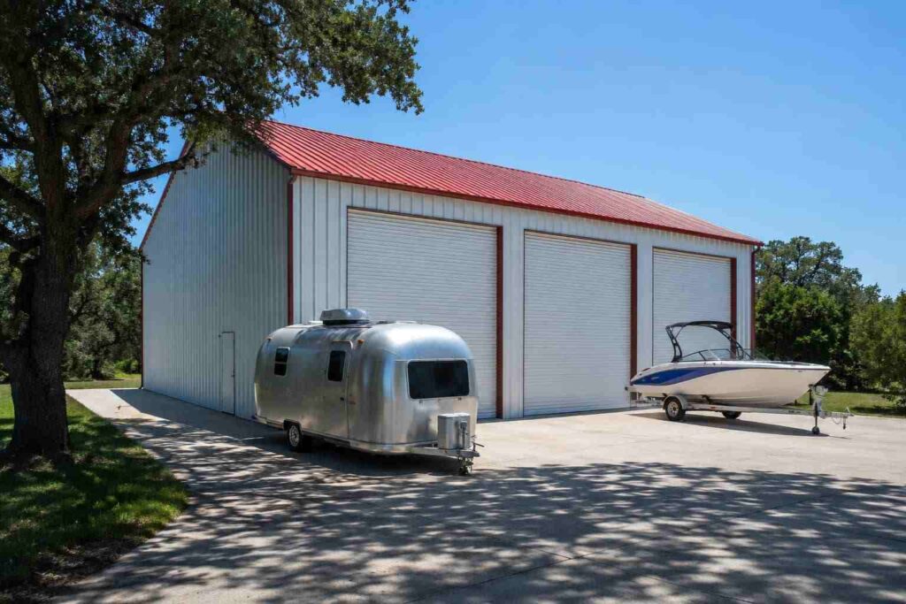 White metal building kit with red roof beside an Airstream trailer and trailered ski boat