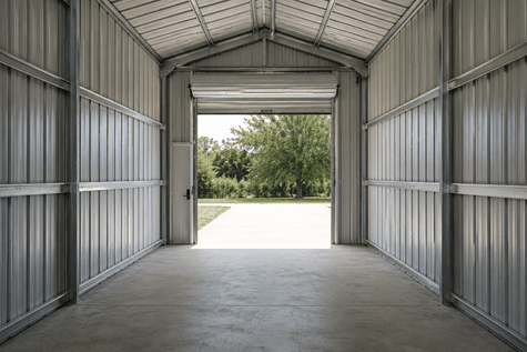 Metal garage interior with galvanized steel panels and roll-up door open to the lawn