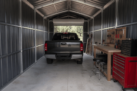 Metal workshop interior with parked pickup truck, wood workbench, pegboard and red tool cabinet